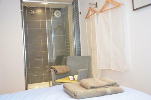 a bedroom with a bed and a chair and a shower at Vesta Cottage, Orford in Orford