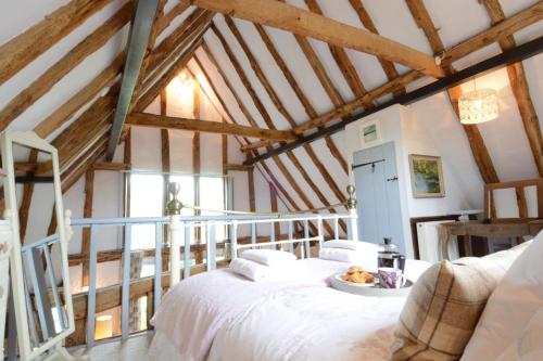 Wassicks Cottage, Haughley في Haughley: غرفة نوم بسرير ابيض في غرفة عوارض خشبية
