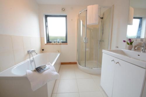 ein Bad mit einer Badewanne, einer Dusche und einem Waschbecken in der Unterkunft Upper Lodge, Shotley 