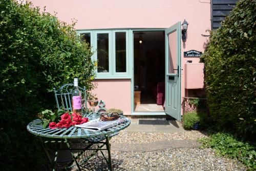 a table with fruit on it in front of a pink house at Seafarers in Fressingfield