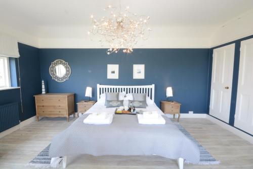 ein blaues Schlafzimmer mit einem großen Bett und einem Kronleuchter in der Unterkunft Holly Lodge in Aldeburgh