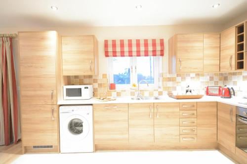 a kitchen with a washing machine and a microwave at Red Robin, Whepstead in Whepstead