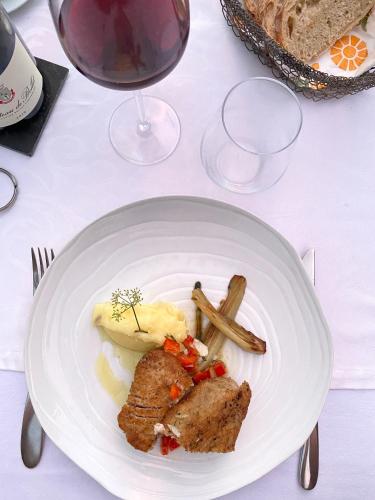 a white plate with food on a table with wine glasses at La Bastide du Beausset-Vieux in Le Beausset