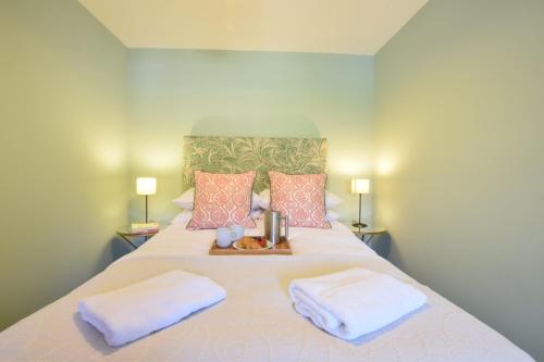 ein großes Bett mit zwei Kissen und einem Tablett darauf in der Unterkunft Seawall Cottage, Aldeburgh in Aldeburgh