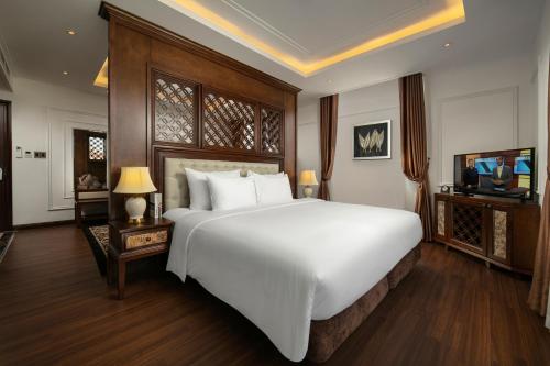 a bedroom with a large white bed and a television at The Q Hotel in Hanoi