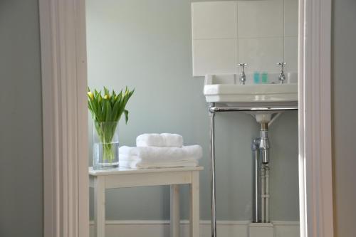 a bathroom with a sink and a table with towels at Lavender House, Aldeburgh in Aldeburgh