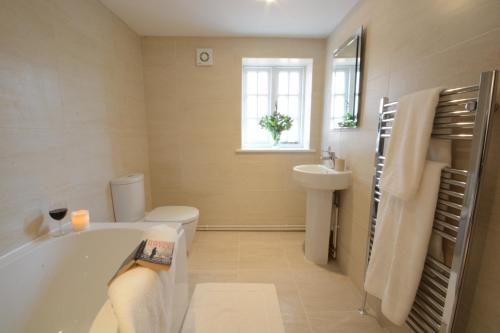 a bathroom with a tub and a toilet and a sink at Southwold Arms Apartment in Southwold