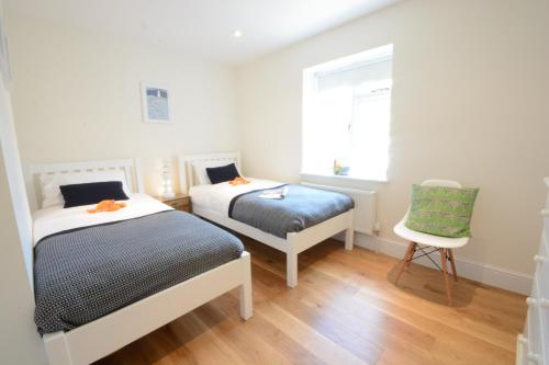 a bedroom with two beds and a chair at Southwold Arms Apartment in Southwold