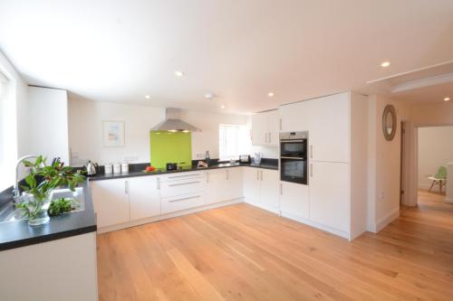 a kitchen with white cabinets and a hardwood floor at Southwold Arms Apartment in Southwold