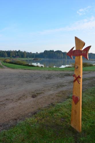 a wooden pole with a cross on the grass at Putraimi. in Princmuiza