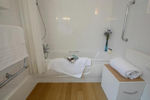 a white bathroom with a bath tub with towels at Rippleway, Walberswick in Walberswick