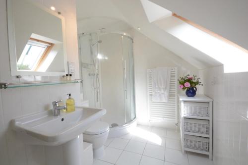 a white bathroom with a shower and a sink at Seadrift in Westleton