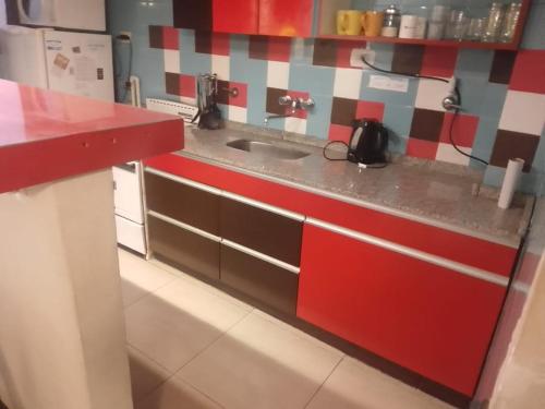 cocina con encimera roja y fregadero en Departamento Céntrico en Villa Carlos Paz