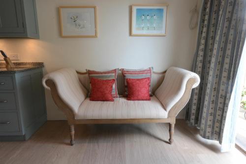 a white couch with two red pillows in a room at 2 The Bays, Thorpeness in Thorpeness