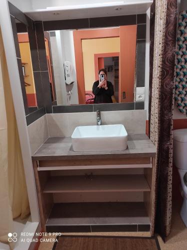 a person taking a picture of a sink in a bathroom at Afrique Appartement de 42m2 à la montagne in Eaux-Bonnes