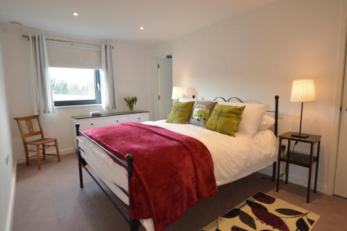 um quarto com uma cama grande e um cobertor vermelho em Rush House, Eastbridge em Westleton