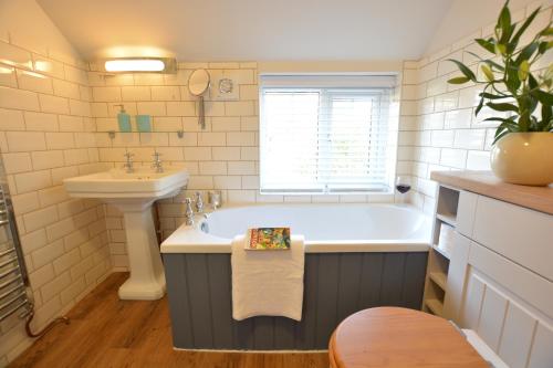 a bathroom with a bath tub and a sink at Little Turnpike Cottage, Melton in Woodbridge