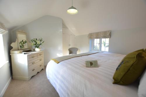 a bedroom with a white bed with a book on it at Little Turnpike Cottage, Melton in Woodbridge