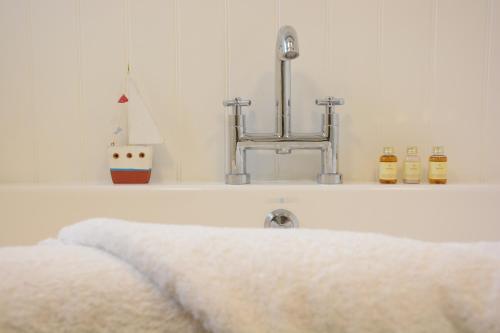 a white sink with a towel on a shelf at Pudding Cottage, Westleton in Westleton