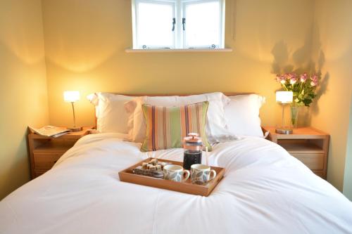 a white bed with a tray on top of it at Harriet's Cottage, Southwold in Southwold