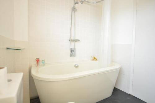 een badkamer met een wit bad en een douche bij Aldeburgh Lodge Gardens in Aldeburgh