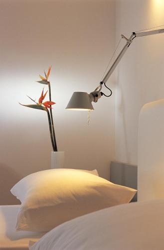 a lamp with a flower in a vase next to a bed at The Majestic Hotel in Fira
