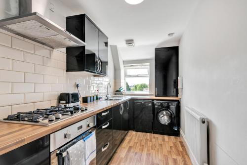 cocina con electrodomésticos en blanco y negro y fogones en Cool and Chic Duffield Road Apartments, en Derby