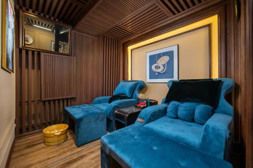 two blue chairs and a couch in a room at The Q Hotel in Hanoi