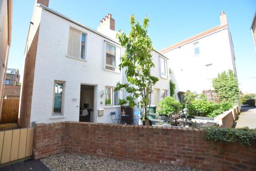 a white house with a brick wall at Mycroft, Southwold in Southwold