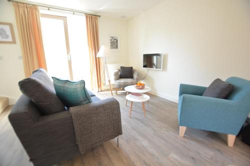 a living room with two chairs and a table at Mycroft, Southwold in Southwold