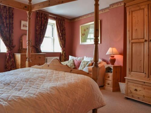 a bedroom with a large bed and a window at Old Saddlers Cottage in Ireby