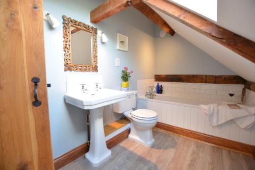a bathroom with a sink and a toilet and a bath tub at Wheelwright's Barn in Halesworth