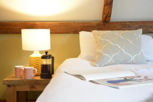 a bed with a lamp and a book on it at Wheelwright's Barn in Halesworth