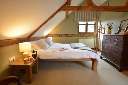a bedroom with a bed and a table with a lamp at Wheelwright's Barn in Halesworth