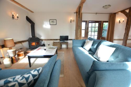 a living room with two blue couches and a fireplace at Wheelwright's Barn in Halesworth