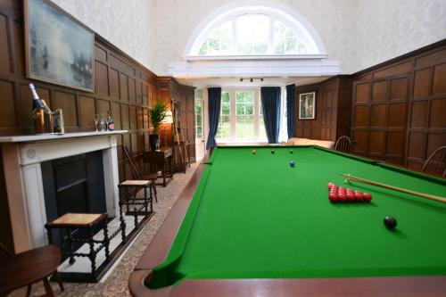 a living room with a pool table and a fireplace at Henstead Hall in Beccles