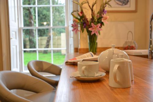 a wooden table with two cups and a vase with flowers at Henstead Hall in Beccles