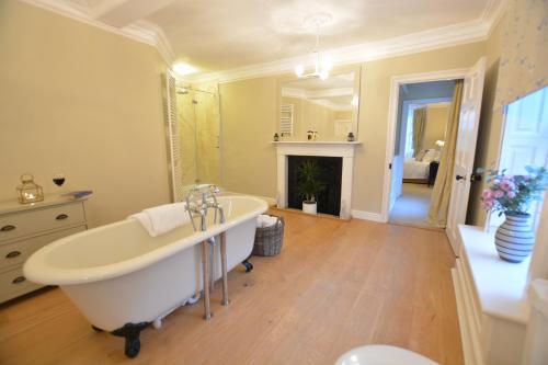 a bathroom with a white tub and a fireplace at Henstead Hall in Beccles