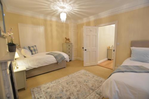 a bedroom with two beds and a door with a rug at Henstead Hall in Beccles