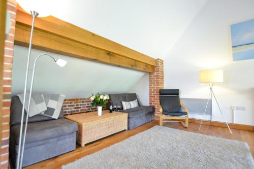 a living room with a couch and a chair at Two Chantry Barns, Orford in Orford