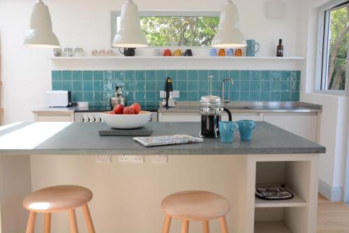 a kitchen with a counter with two stools at 2 Pink Cottages, Aldeburgh in Aldeburgh