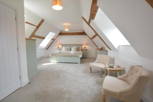 un dormitorio en el ático con 2 camas y una silla en Ploughman's Green, Blythview en Blythburgh