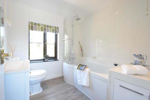 a bathroom with a tub and a toilet and a sink at Pine Cottage in Woodbridge