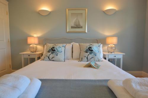 a bedroom with a large white bed with two lamps at Neptune in Aldeburgh