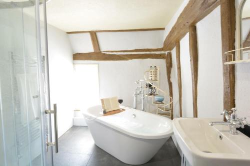 a bathroom with a white tub and a sink at The White House with Studio in Homersfield