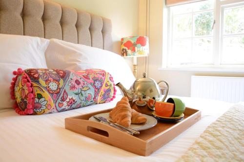 a tray of food and croissants on a bed at Church Farm Cottage, Dunwich in Westleton