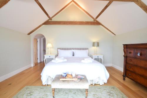 a white bedroom with a large bed and a dresser at Cannons in Southwold