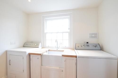 a white kitchen with a sink and a window at Cannons in Southwold