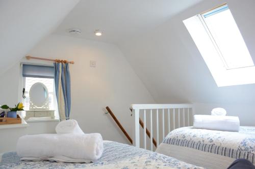 a white bedroom with two beds and a window at The Moorings, Orford in Orford