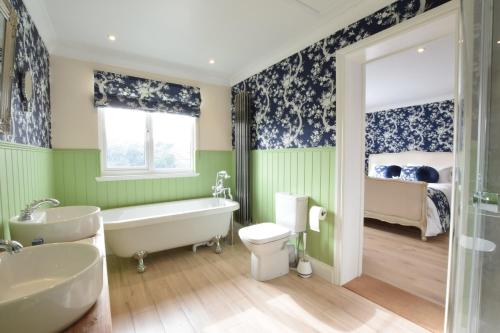uma casa de banho com uma banheira, um WC e uma cama em Napier House, Southwold em Southwold